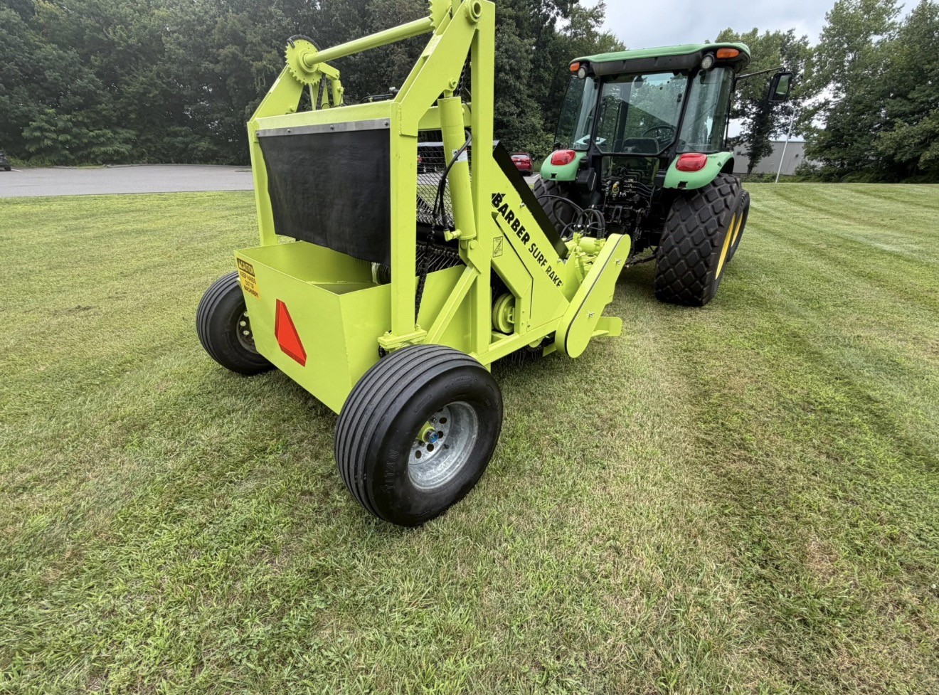 Tractor pulling professional Barber Surf Rake beach-cleaning equipment