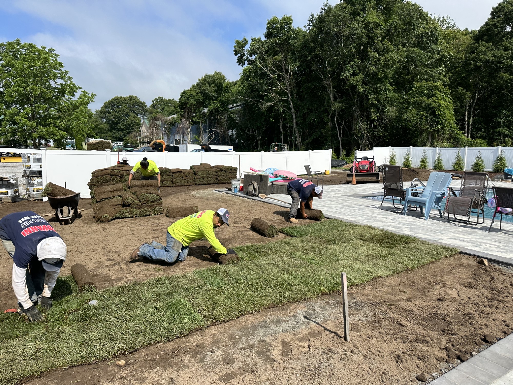 Landscapers laying fresh sod beside a newly built paver patio