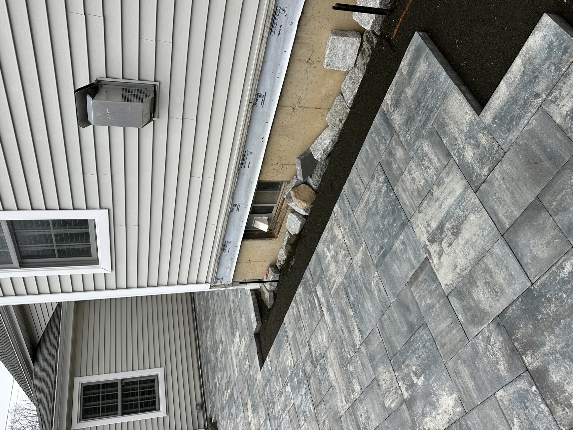 Paver patio and stone detail beside a home