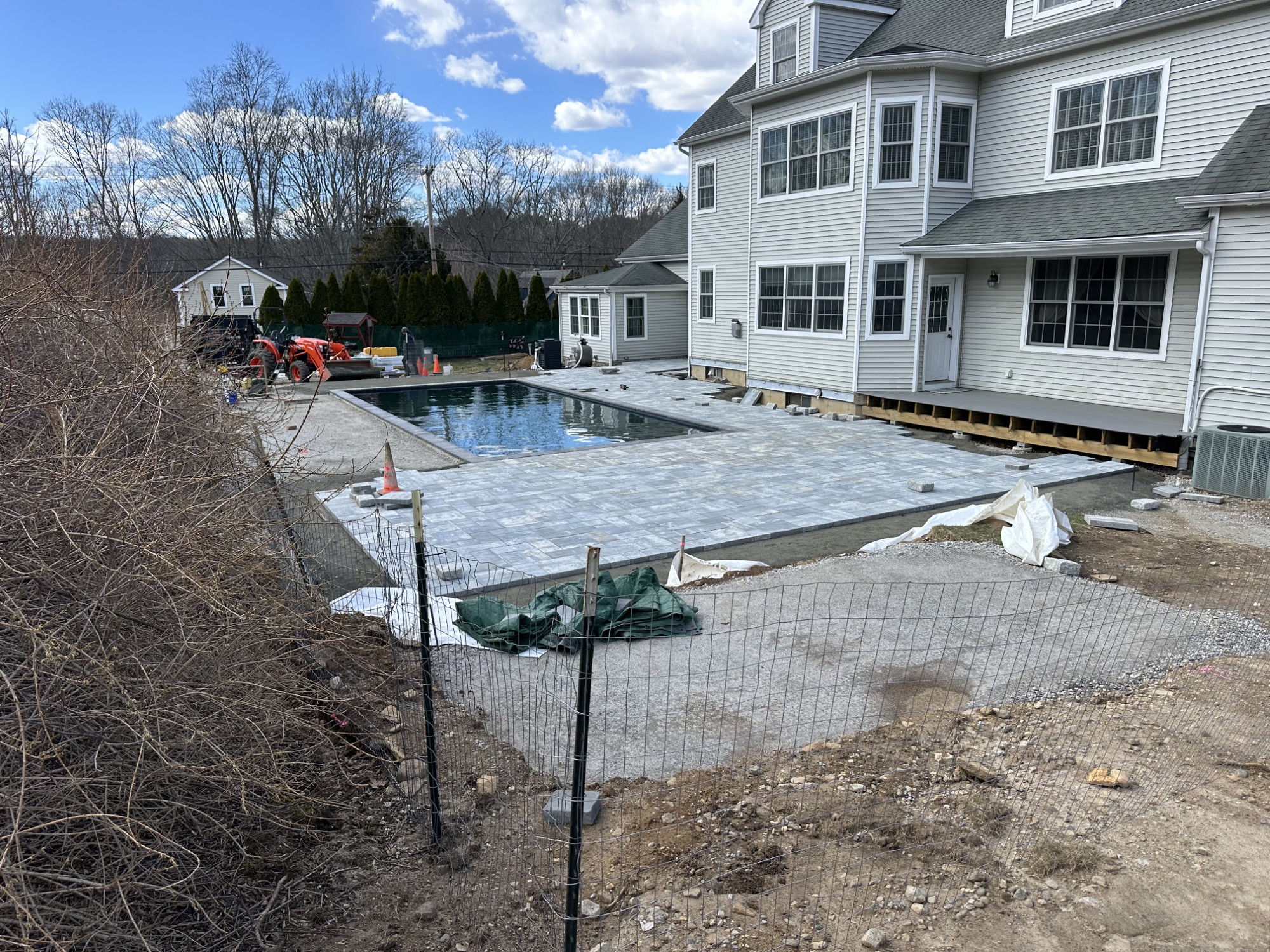 Paver patio installation around a backyard swimming pool